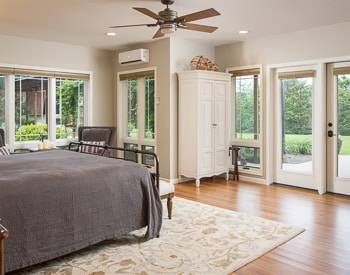 King bed with a dark grey bedspread, Terrace level with panoramic mountain views. Cream colored armoire 